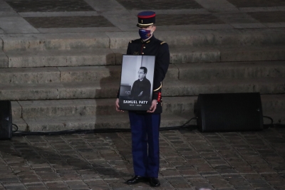 A Republican Guard holds a portrait of Samuel Paty